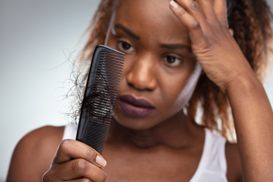 Woman looking concerned while holding a comb with shed hair, representing hair shedding and emotional stress about hair changes.