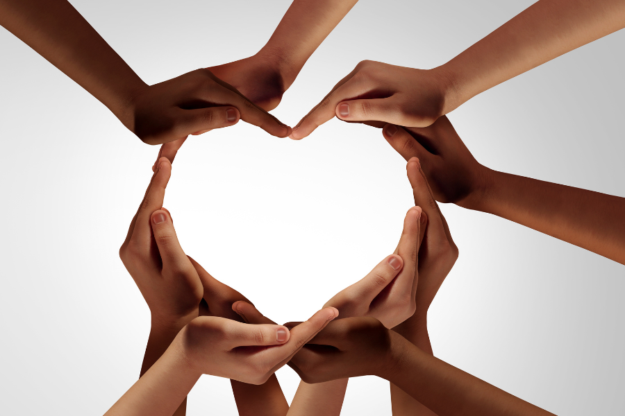 Diverse hands forming a heart shape in the center, symbolizing community care, inclusion, and support.