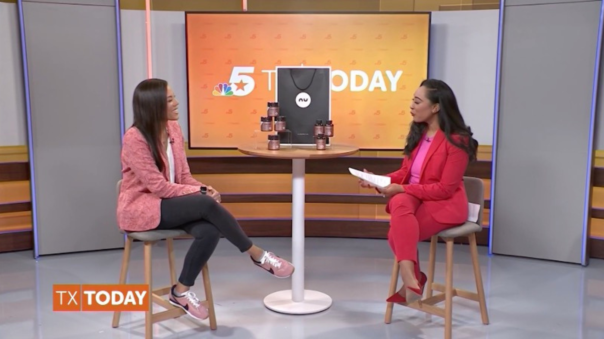 Two women sitting on stools in a studio setting with a TV screen displaying 'TX TODAY'.